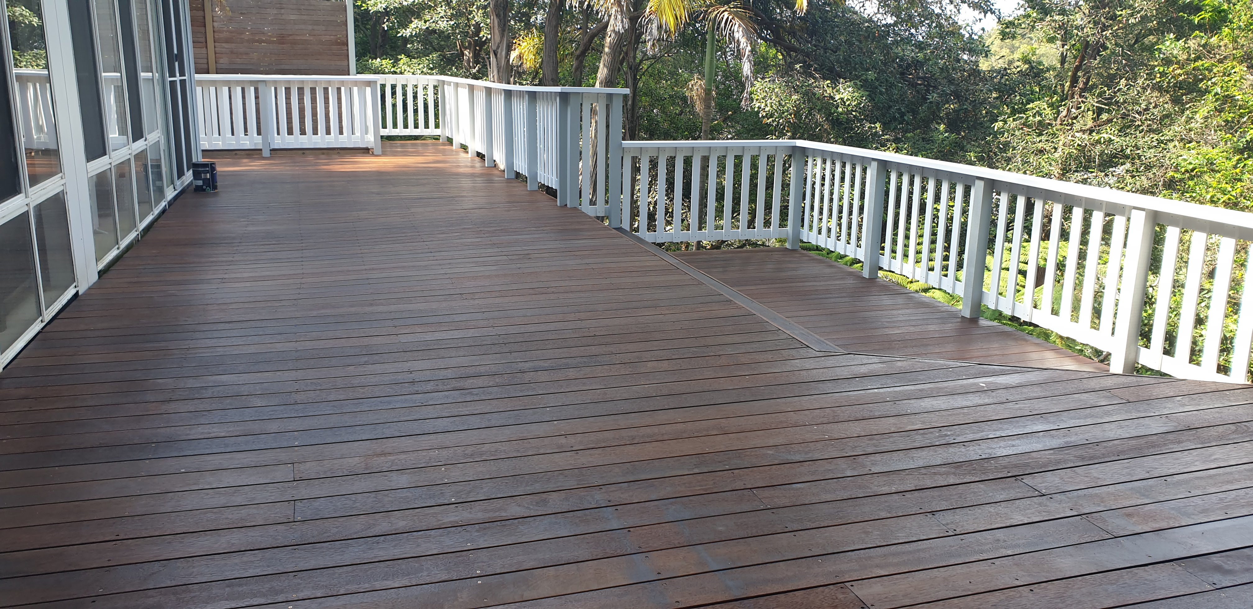 Large freshly stained deck with white timber railing — Northern Beaches
